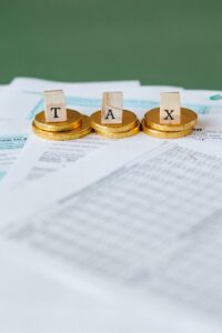 Image mise en scène de pièces d'or avec des tuiles de lettres fiscales sur des documents.
