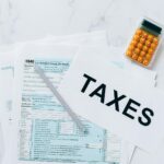 Vue de dessus des formulaires fiscaux, d'une calculatrice et d'un stylo pour la préparation des impôts.