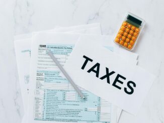 Vue de dessus des formulaires fiscaux, d'une calculatrice et d'un stylo pour la préparation des impôts.