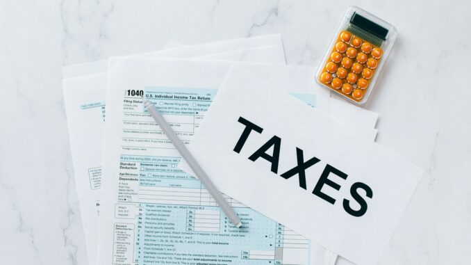 Optimisation fiscale Vue de dessus des formulaires fiscaux, d'une calculatrice et d'un stylo pour la préparation des impôts.